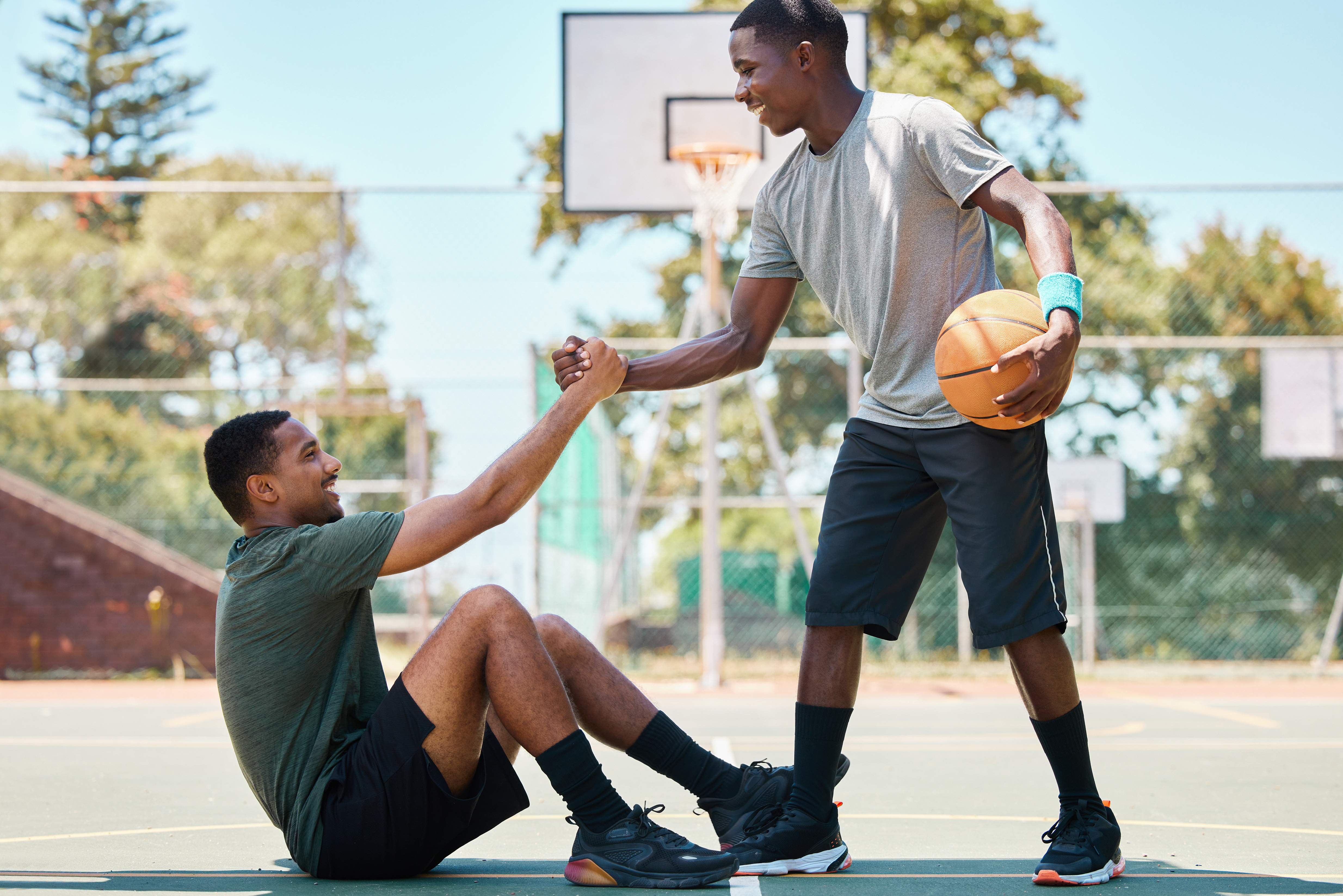 someone helping someone up, after falling on the basketball court