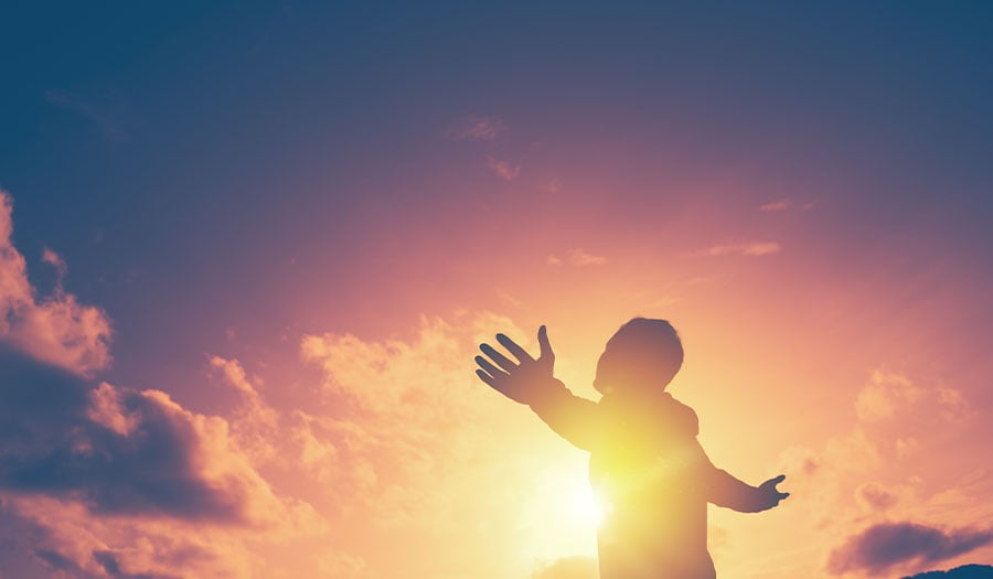 Man with arms outstretched looking at sunrise