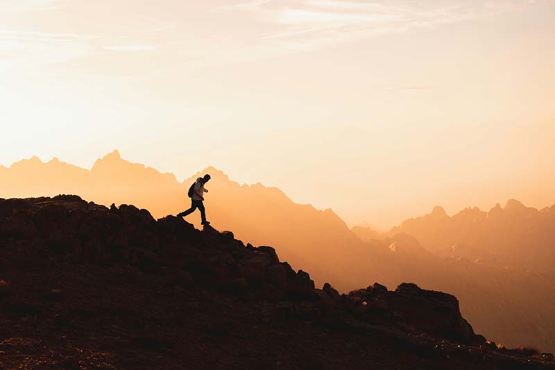 Silhouette of a man walking down a rocky mountain path 